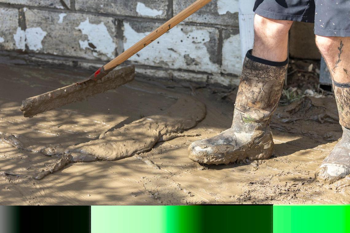 Skyler Tackett cleans up mud from a house on Mullins School Street in Pike County, Ky., Heavy rainfall lead to flooding throughout Kentucky over the weekend.