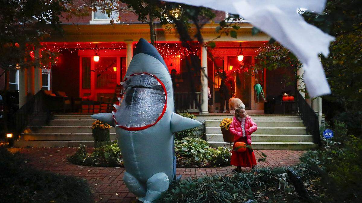Finley Insko, 12, left, and Ellen James Hilton, 6, both of Lexington, Ky., leave a house after receiving candy while trick-or-treating along Sayre Avenue in Lexington, Oct. 31, 2019.