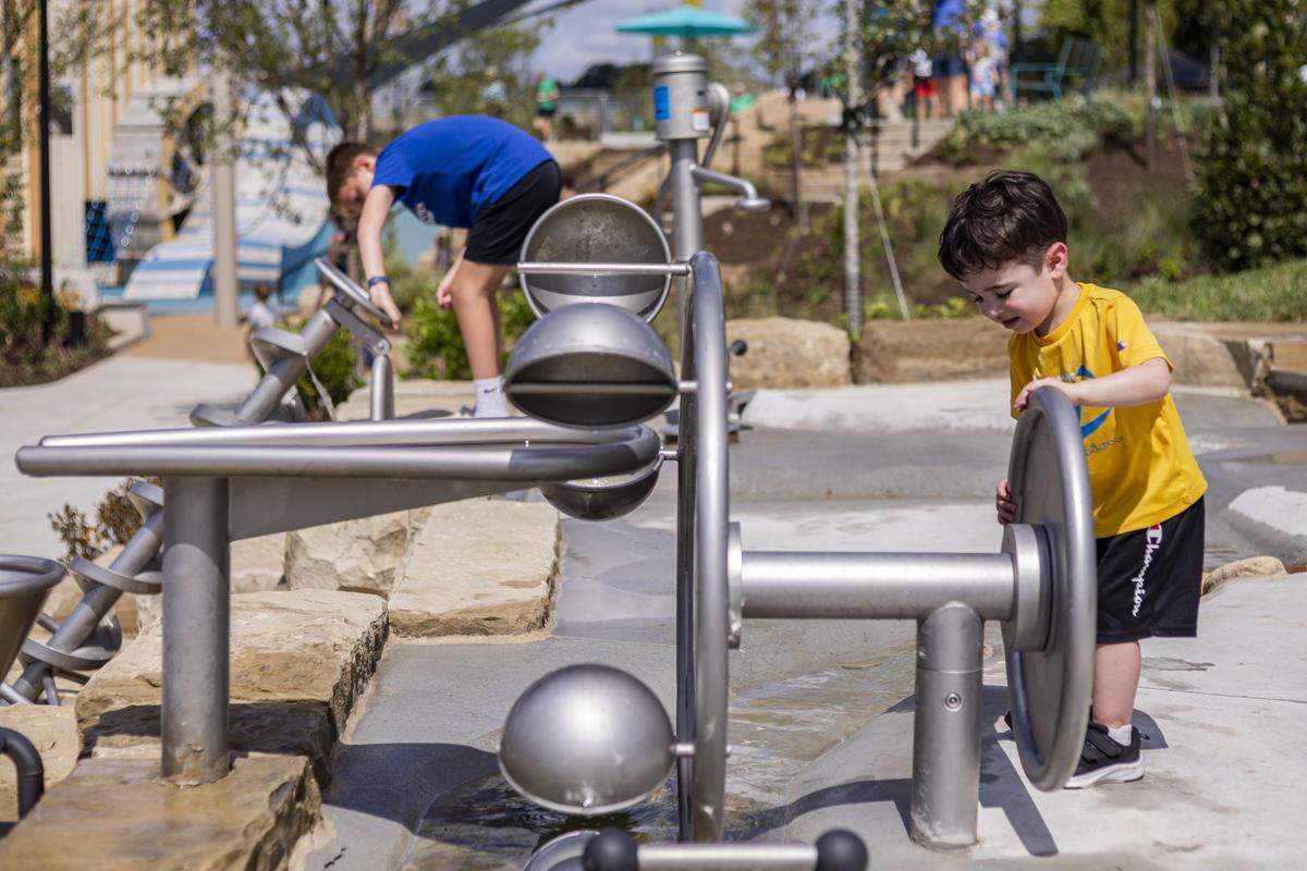 Manny Hernandez, right, plays with the water features during the opening of Gatton Park on Saturday, Aug. 23, 2025, in Lexington, Ky. 