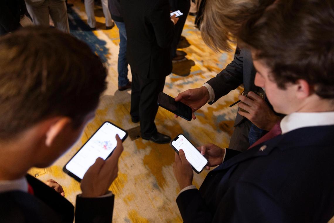Supporters look at their phones for election results during an election event for Republican gubernatorial Daniel Cameron at the Louisville Marriott in Louisville, Ky, Tuesday, November 7, 2023.