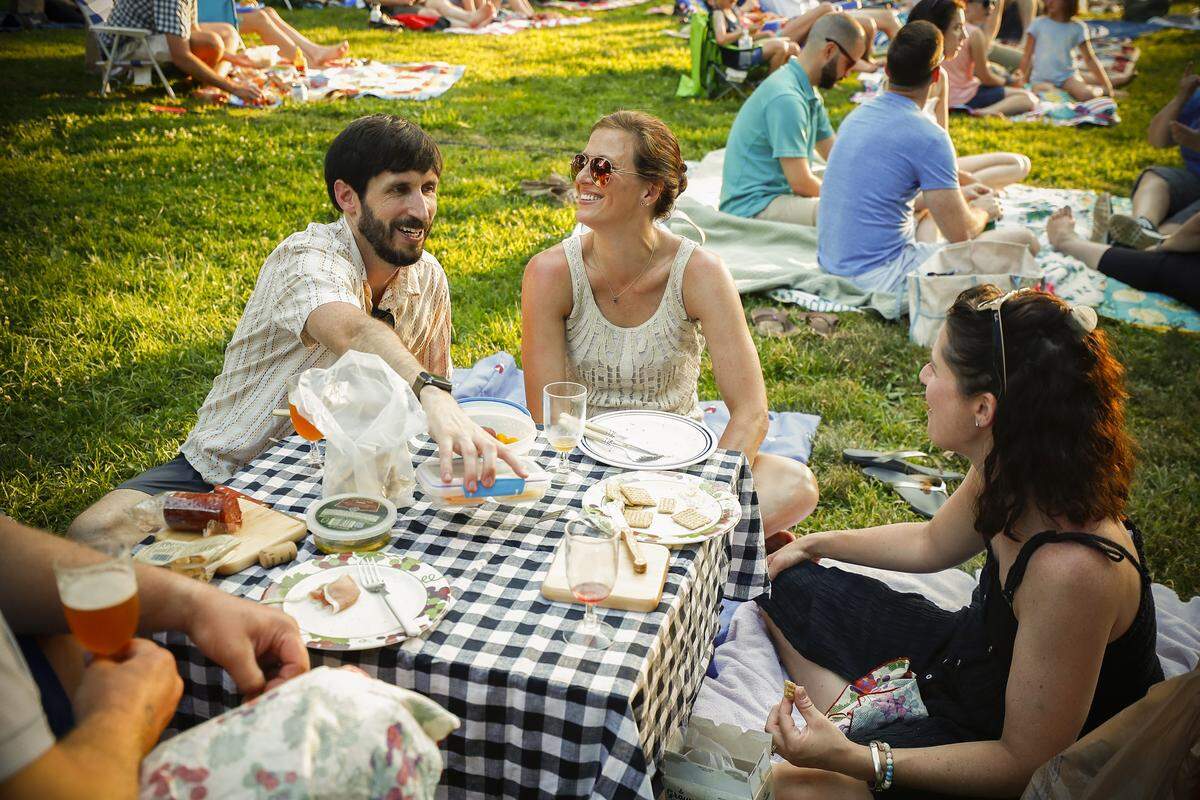 Jesse Dean, from left, Laura Murphy, and Stephenie Hoelscher, all of Lexington, Ky., have a picnic before “Broadway Under the Stars” presented by the Kentucky Conservatory Theatre for SummerFest 2019 at Woodland Park in Lexington, Friday, July 5, 2019. Broadway Under the Stars features a medley of performances from previous SummerFest productions. Sunday’s show begins in Woodland Park at 8 p.m.
