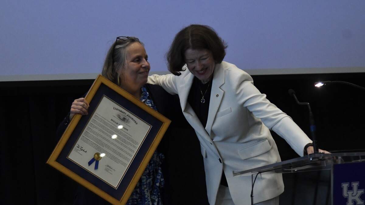 University of Kentucky faculty trustee Karen Petrone (left) presents faculty trustee Hollie Swanson with a framed resolution highlighting her commitment to UK during Swanson’s final board meeting on Tuesday, June 30, 2026, at Kroger Field in Lexington, Kentucky.