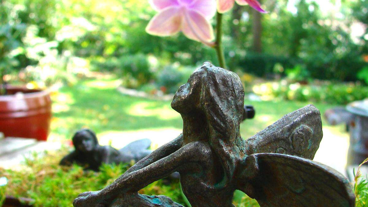 An iron fairy from Wilson Nurseries is part of a fairy garden that also includes Irish moss, a miniature orchid, glass baubles and a recycled pottery container as a pond.