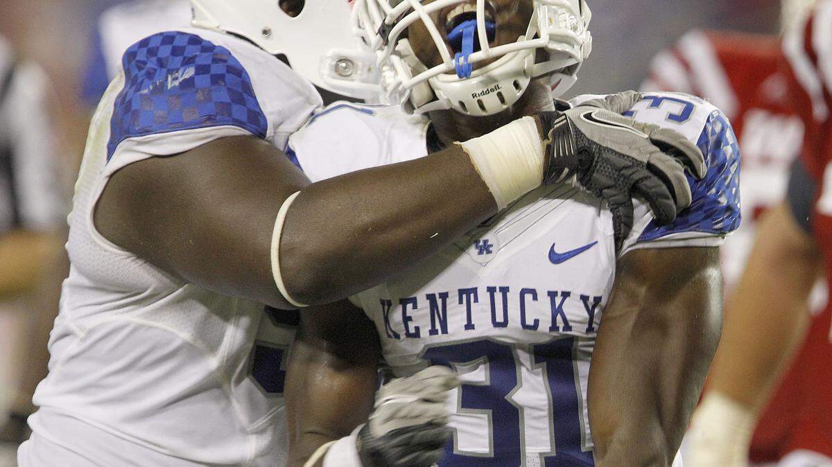 Mikie Benton (31) got a hug from Donte Rumph after tackling Western Kentucky running back Bobby Rainey in the opener.