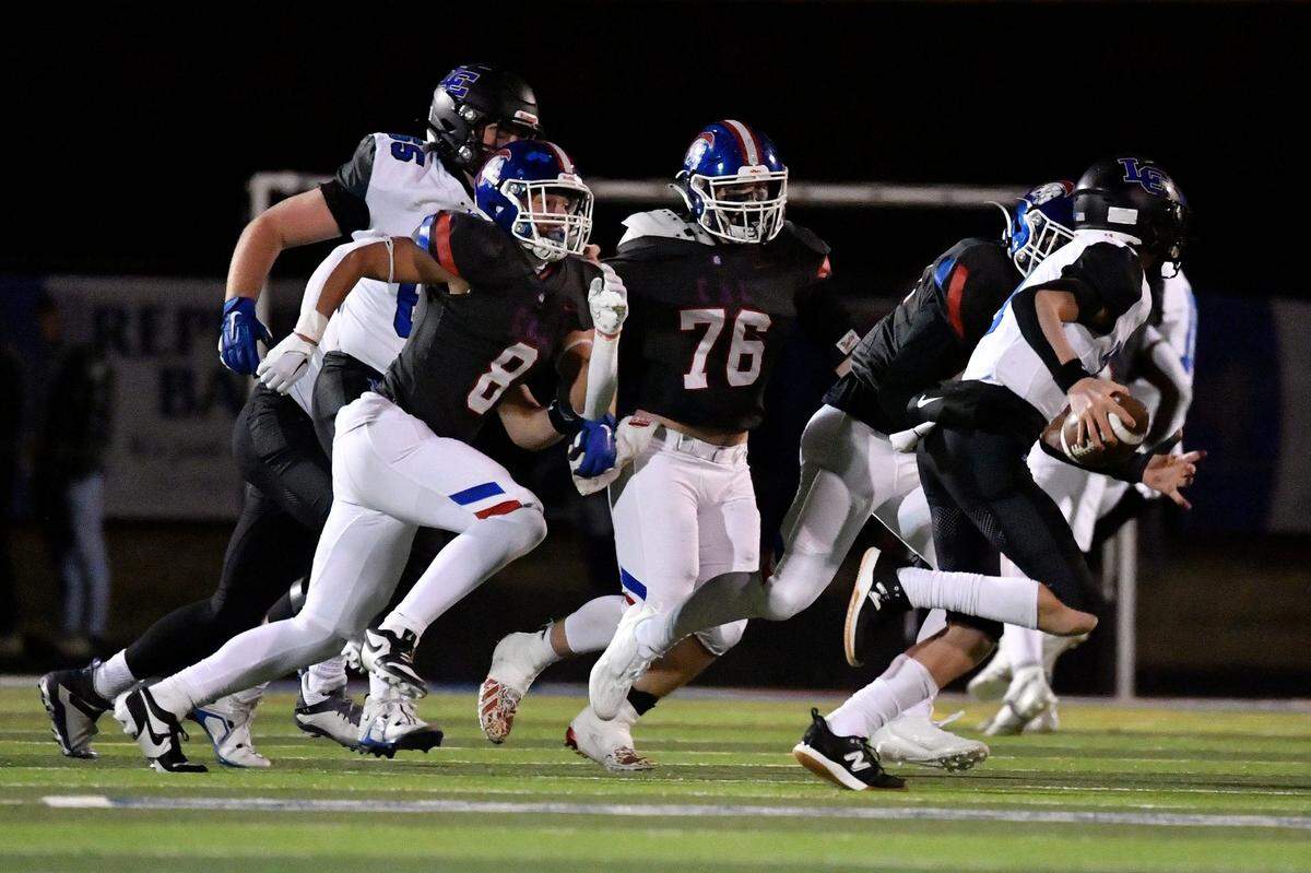 Lexington Catholic’s Jackson Wasik, right, is chased out of the pocket by Christian Academy-Louisville’s Jackson Settle (8) and Nathan Carlisle during the second half of Friday’s playoff game.