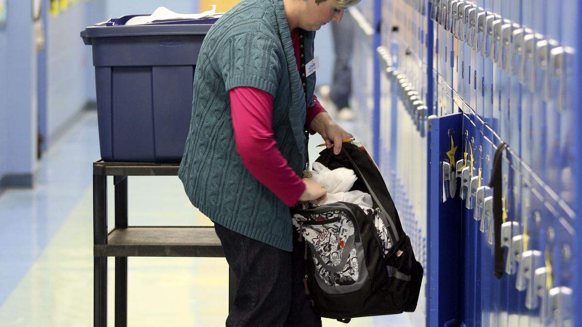 Monica Hall, director of the family resource center at Booker T. Washington Academy, placed bags of food into students' backpacks at Booker T. Washington. Family resource centers were created to help low-income students overcome barriers to academic achievement, but they've been severely underfunded in recent years.