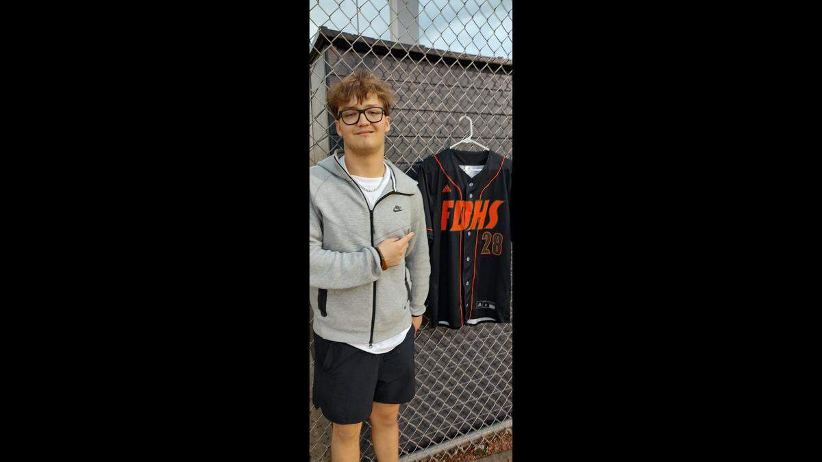 Mike Perrine, the older brother of Matthew Perrine, posed with his baseball jersey at the baseball field at Frederick Douglass High School in Lexington, Ky., Tuesday night. Matthew, 17, died in a car crash Saturday.