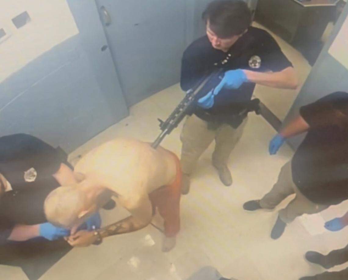 A Montgomery Co. jail deputy points a pepper gun at the back of Kevin Hall while he is handcuffed.