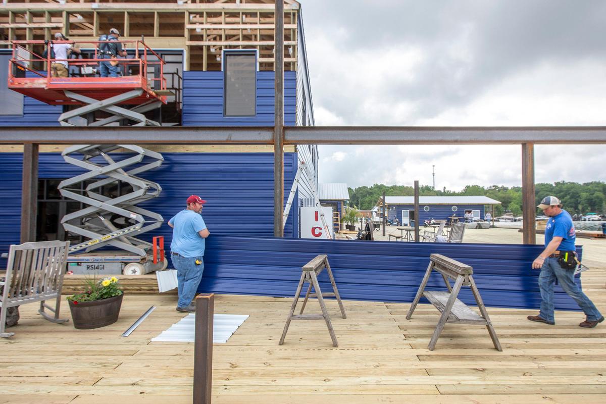 Scott Smith, left, and Jared Foster, along with Dustin Dishman and Jeremy Rector, on lift, from left, install siding for the new store at Conley Bottom Resort near Monticello, Ky., on Lake Cumberland on Tuesday, May 19, 2020.