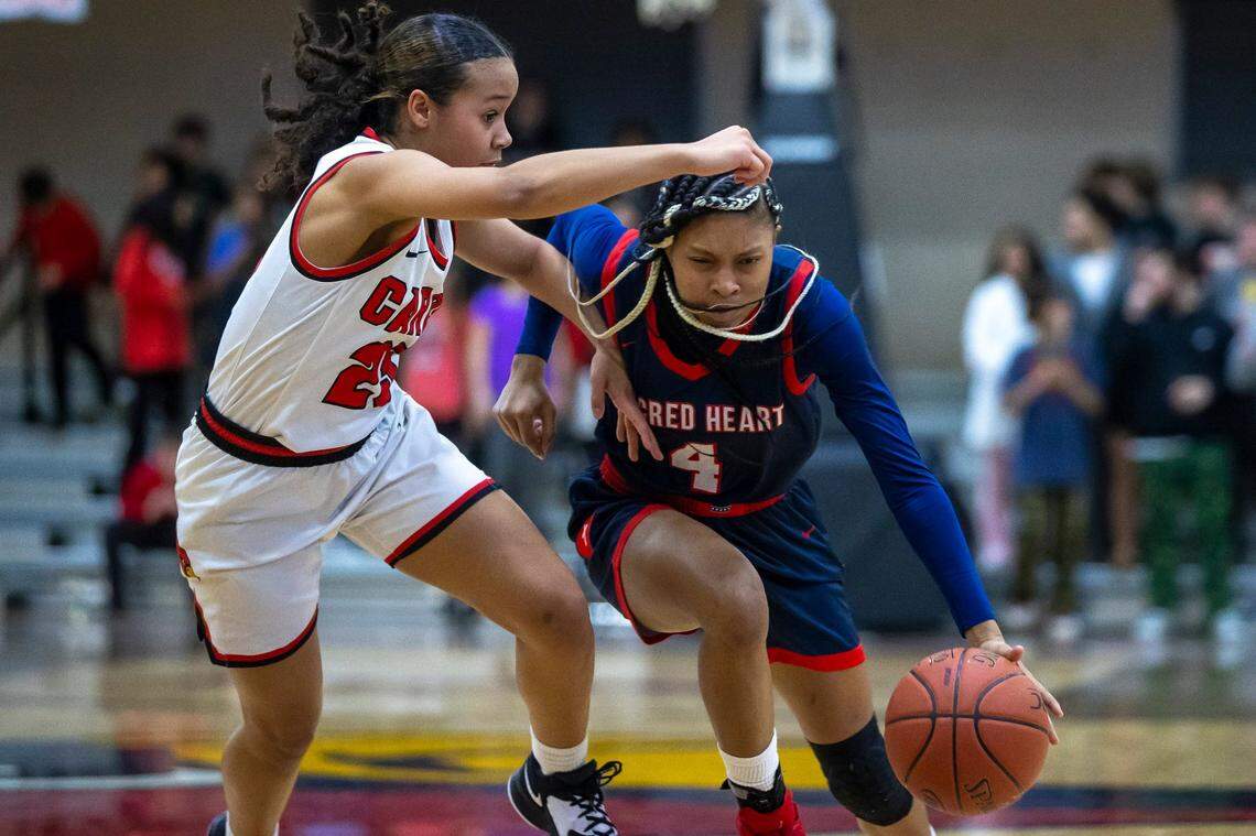 Sacred Heart’s Triniti Ralston (4) drives the ball past George Rogers Clark’s Anaya Chestnut (25) during a game in Winchester on Feb. 7.