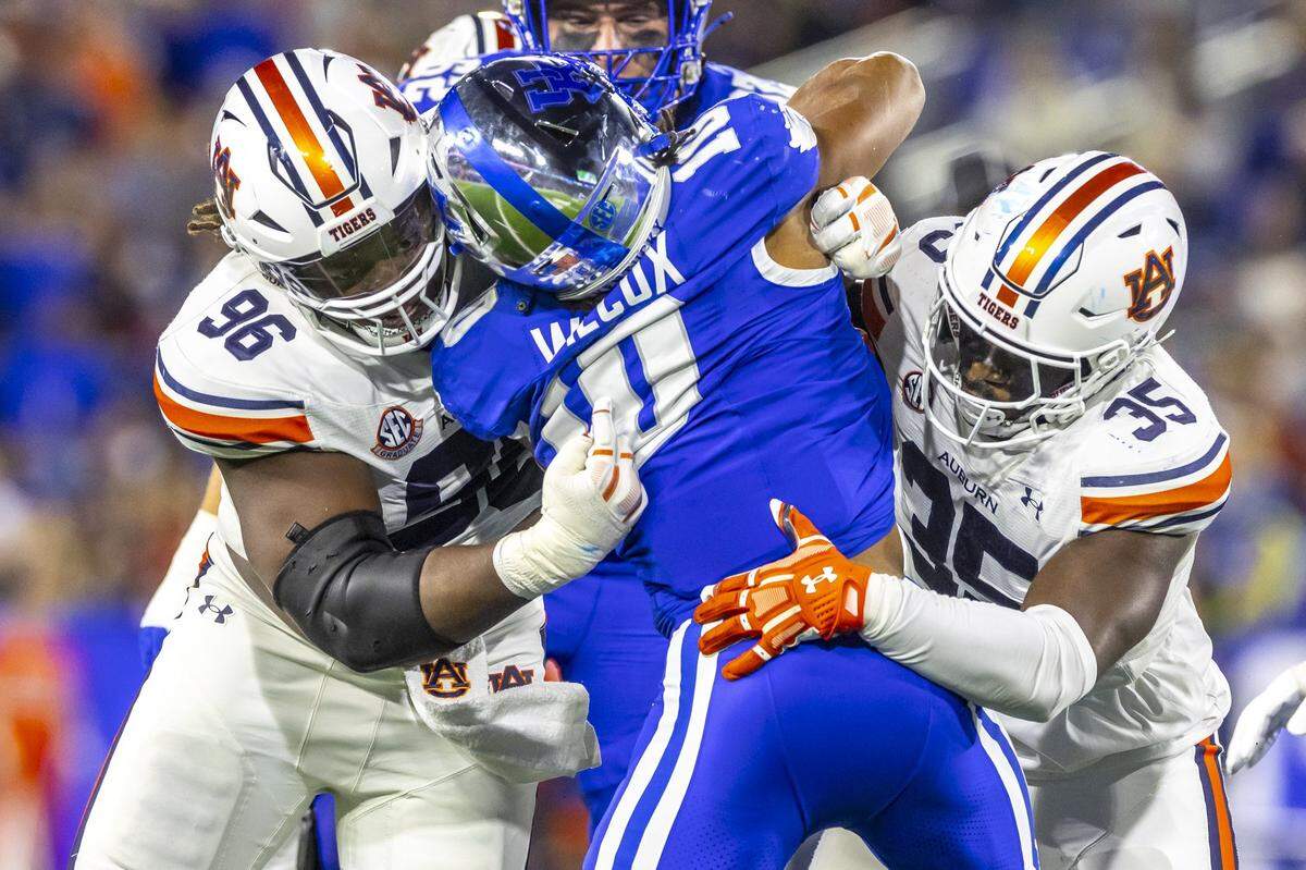 Kentucky running back Jamarion Wilcox (10) is tackled by Auburn defensive lineman Philip Blidi (96) and nose tackle Jalen McLeod (35) during Saturday’s game at Kroger Field.