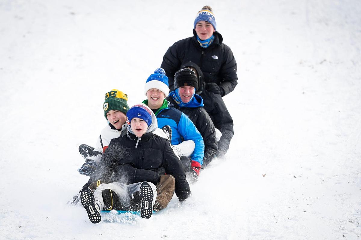 Riley Schneider, 16, Sam Sizemore, 16, Deacon Carter, 15, Finn Kenny, 15, and Chardy Tierney, 16, all of Lexington, Ky., sled down the hill behind the former Shriners Hospital on Richmond Road in Lexington, Ky., Friday, Jan. 7, 2022.