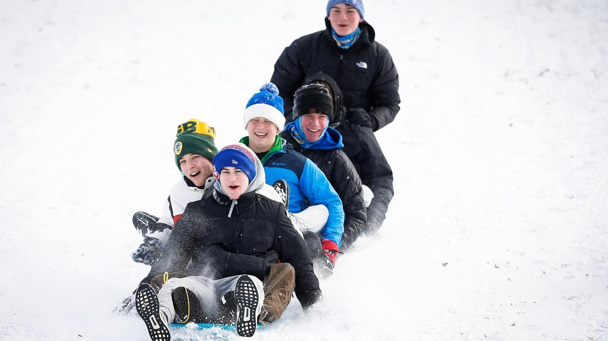 Riley Schneider, 16, Sam Sizemore, 16, Deacon Carter, 15, Finn Kenny, 15, and Chardy Tierney, 16, all of Lexington, Ky., sled down the hill behind the former Shriners Hospital on Richmond Road in Lexington, Ky., Friday, Jan. 7, 2022.
