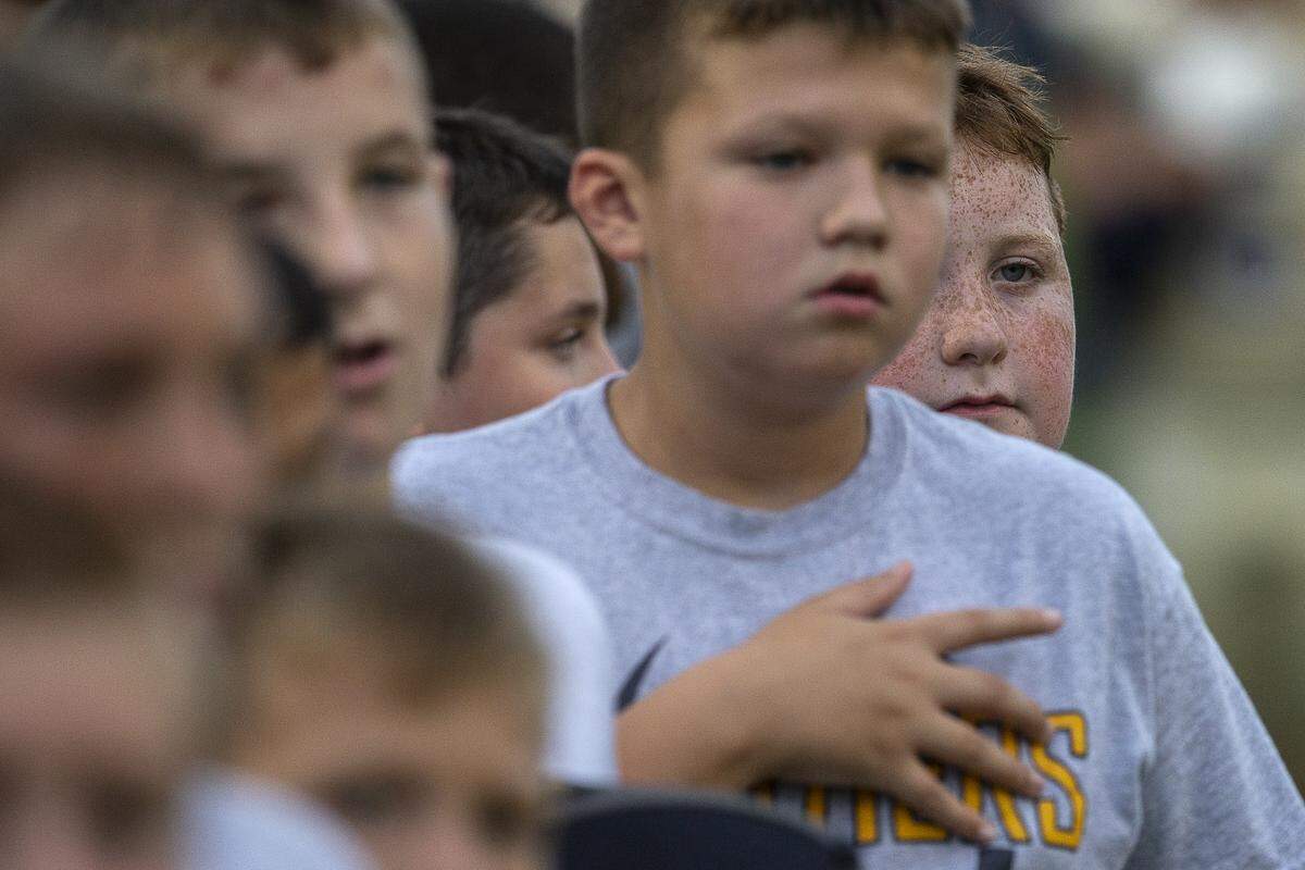 Spectators listen as the national anthem is performed before the start of the game.