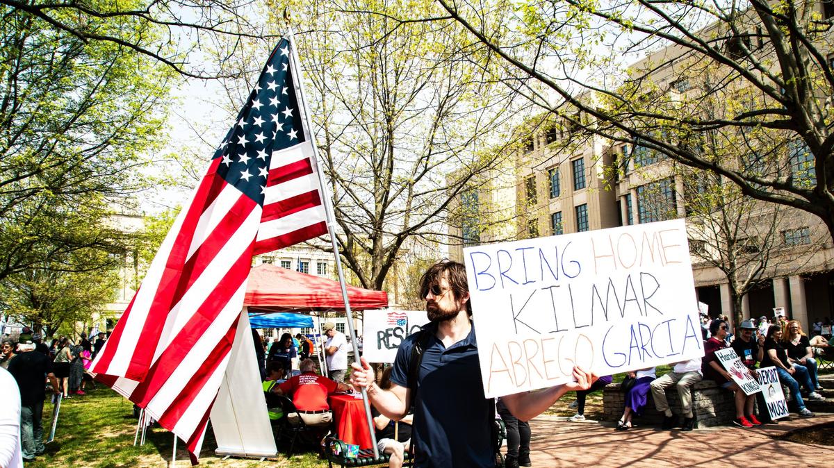 A man holds the American flag and a sign demanding the return of Kilmar Abrego Garcia, the Maryland man mistakenly deported to El Salvador by ICE, during an anti-Trump protest in downtown Lexington, Ky., April 19, 2025.