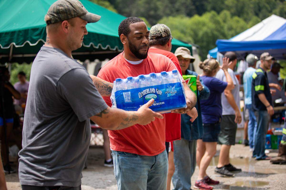 Representative Charles Booker, D-Louisville, helped carry donated water Wednesday for miners in Harlan County who were protesting on train tracks after their former employer, Blackjewel, failed to pay them for their last three weeks of work.
