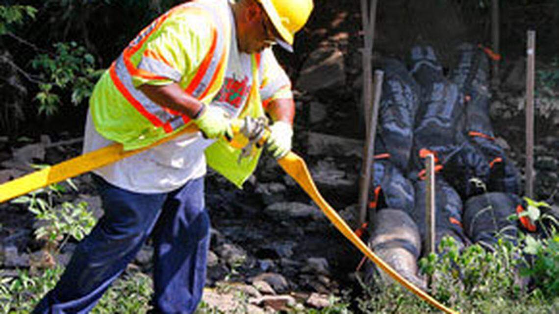Ken Newby with Lexington's water quality division, hooked up hoses in front of sewage collection booms at the site of a sewage leak in Vaughan's Branch Creek in the back of Pine Meadows Park on Tazewell Drive in Lexington Monday. Vaughan's Branch is a tributary of Wolf Run Creek where dead crayfish have been reported.