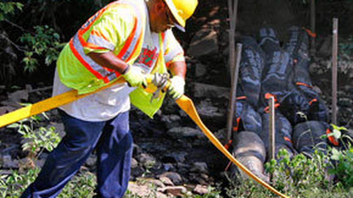 Ken Newby with Lexington's water quality division, hooked up hoses in front of sewage collection booms at the site of a sewage leak in Vaughan's Branch Creek in the back of Pine Meadows Park on Tazewell Drive in Lexington Monday. Vaughan's Branch is a tributary of Wolf Run Creek where dead crayfish have been reported.