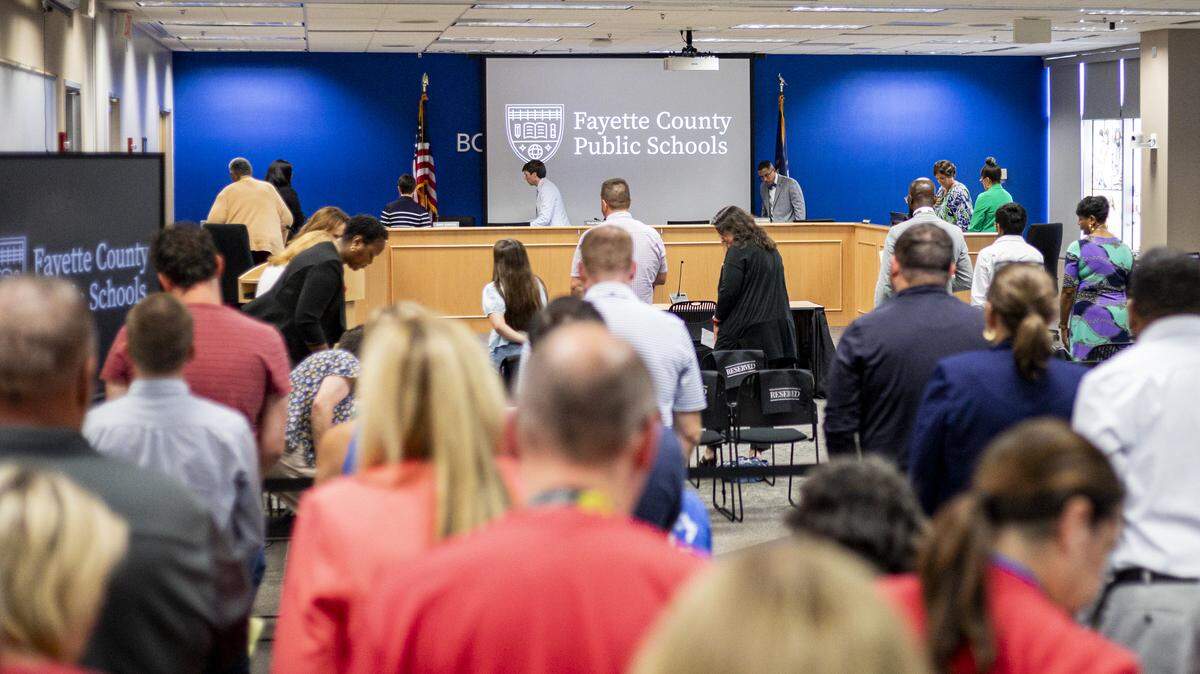 Attendees sit down after the pledge of allegiance during a school board meeting on Monday, Aug. 18, 2025, at Fayette County Public Schools Central Office in Lexington, Ky. 