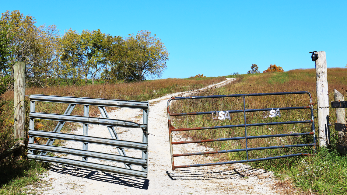 An ere residential gate leans slightly ajar, exposing a winding path leading to the crime scene being processed by Kentucky State Police Post 6, following the arrest of Torilena May Fields on October 11, 2024, in Mount Olivet, Ky.
