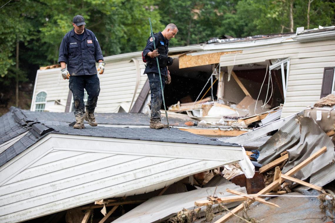 Members of the Lexington Fire Department look through the wreckage of a home while operating as search and rescue units along KY-476 along Troublesome Creek in Breathitt County, Ky., Sunday, July 31, 2022.