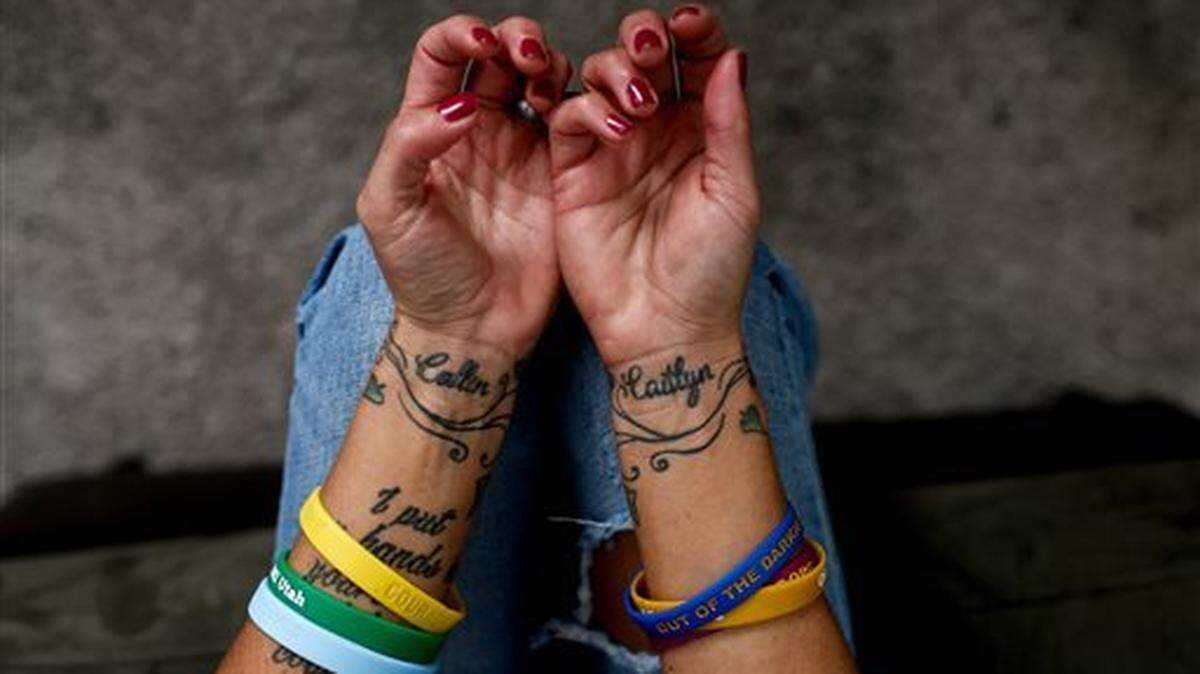 In this Wednesday, Oct. 14, 2015 photo, Taryn Aiken poses for a portrait at her home in Pleasant Grove, Utah. The tattoos on her wrists are the names of her two children, Collin and Caitlyn, and cover the scars from where she cut herself in a suicide attempt.