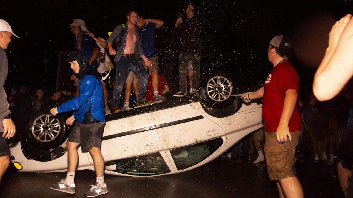 Revelers stand atop an overturned car on State Street on Saturday, September 8, 2018. Fans were celebrating UK’s 27-16 victory over Florida, ending a 31-year losing streak.