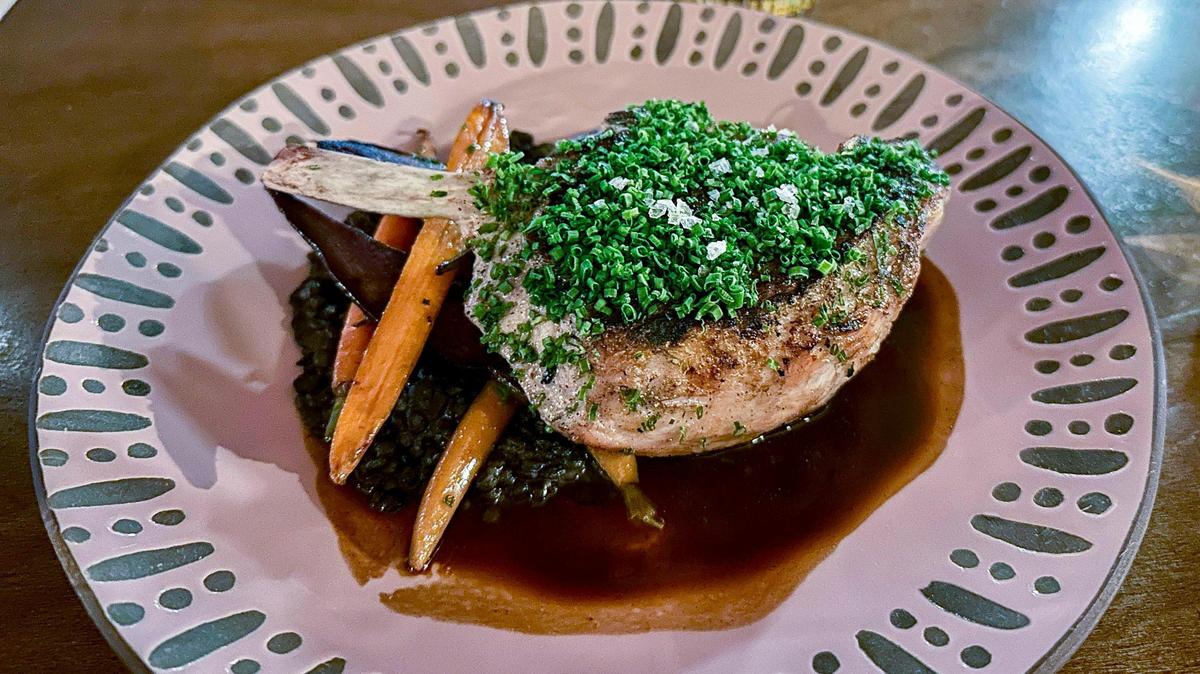 A grilled Berkshire pork chop ($40) with black garlic-fig jus, beluga lentils and braised heirloom carrots at Mileta. “I like to joke, the only thing we buy is Heinz ketchup. We make everything else from scratch,” said chef Alex Green.