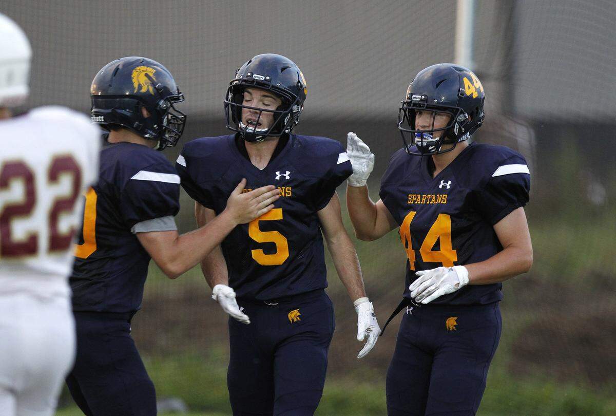 Sayre’s Cole Pennington, left, and Hank Williams congratulate Daniel Clinkinbeard (5) after he ran for a touchdown against Bourbon County last season. The Spartans are coming off an 8-1 campaign.