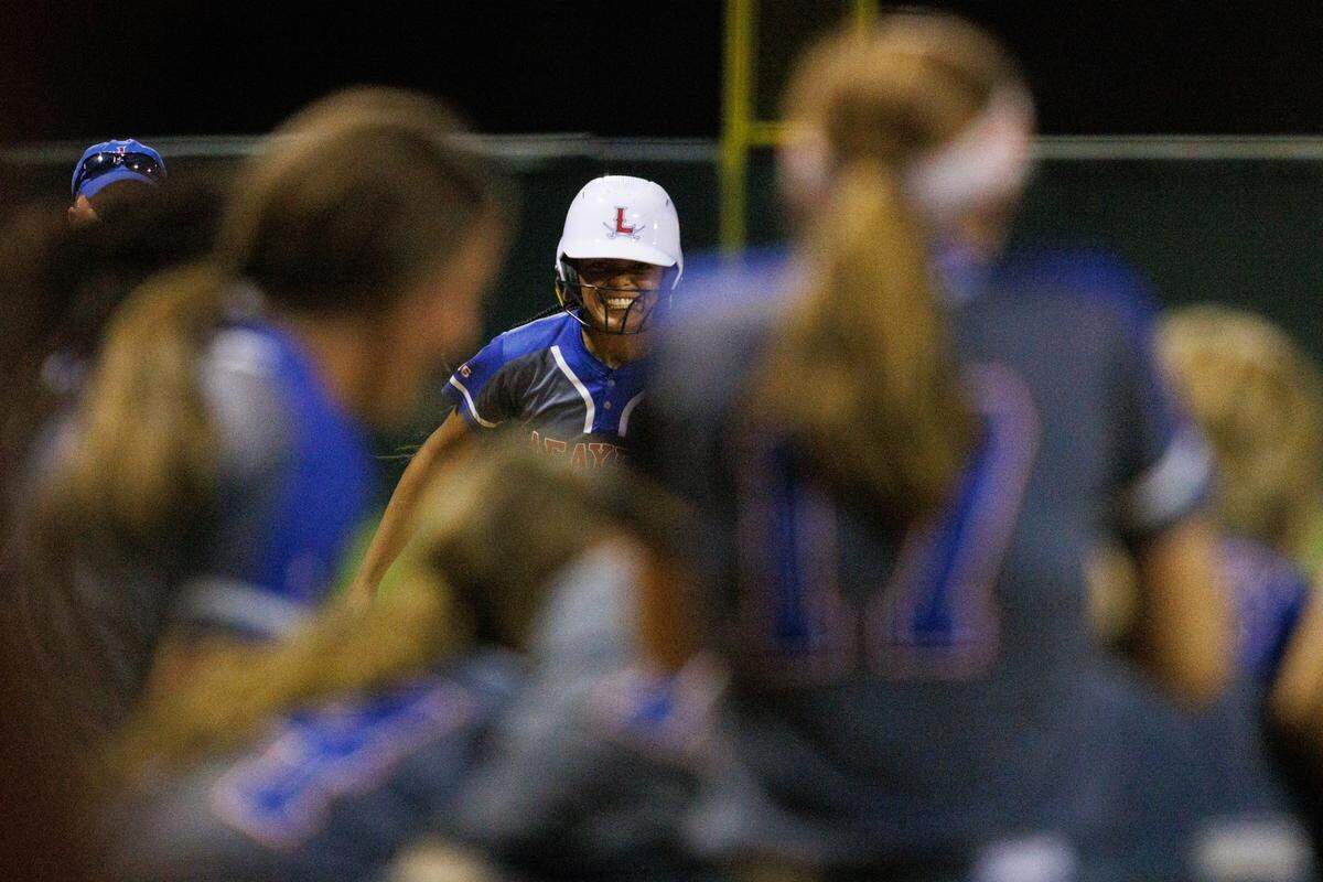 Nora Mack meets her teammates for a celebration at home plate after hitting a two-run homer in the seventh inning that cemented Lafayette’s victory in Tuesday night’s 11th Region Tournament semifinals.