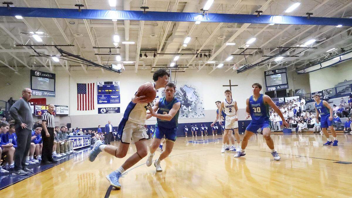 Lexington Catholic's Everett Stuart (23) drives on North Laurel's Jordan Rawlings (2) during the Knight's win, Tuesday, Dec. 2, 2025 at Lexington Catholic High School in Lexington, Ky.