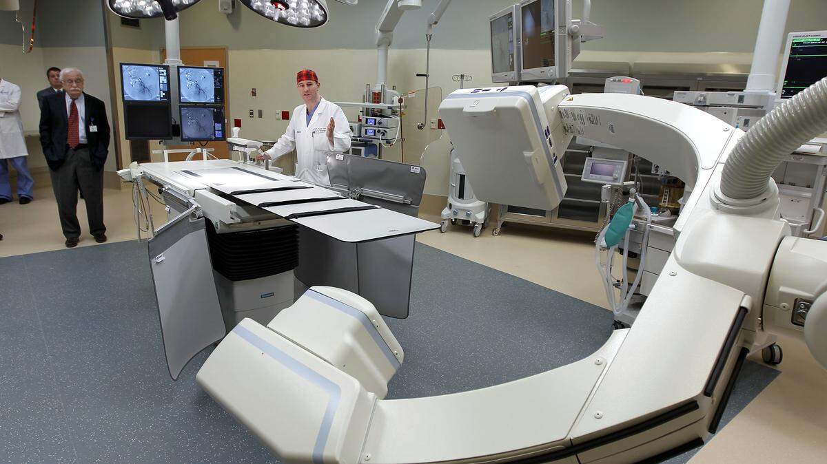 Dr. Justin Fraser, a neurosurgeon, center, talked Wednesday about the capabilities of a new hybrid operating room at UK Chandler Hospital. Built at a cost of about $3.2 million compared to $1 million for a traditional operating room, it features sophisticated imaging and robotic technology.