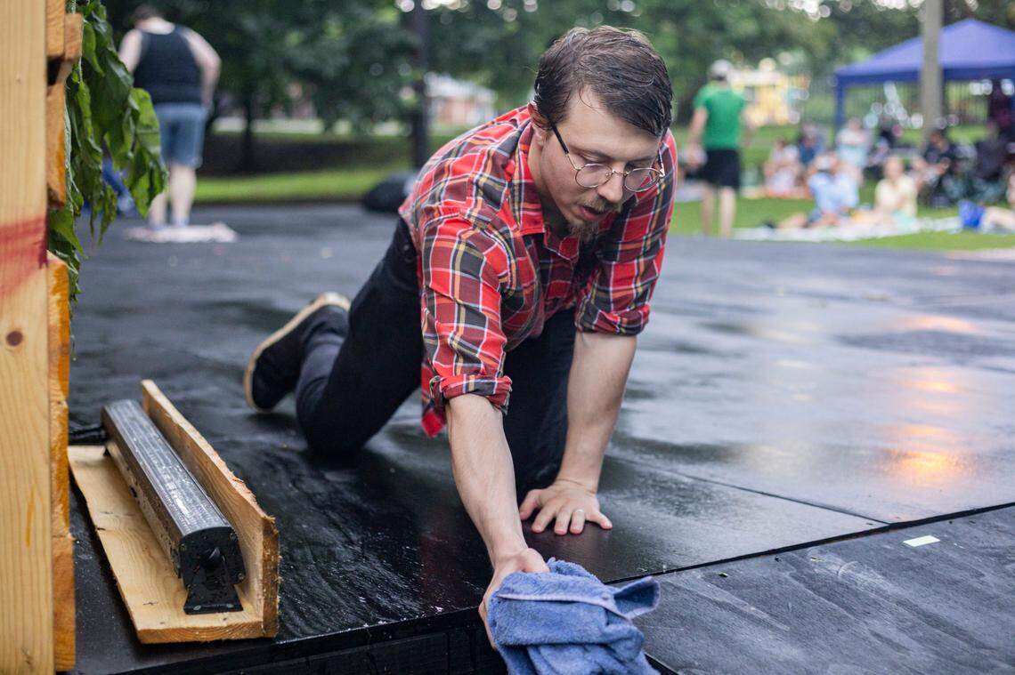 Treyton Blackburn, director of the show, wipes water from the stage after it rained before a showing of Romeo and Juliet on Friday, July 18, 2025, at Woodland Park in Lexington, Ky.