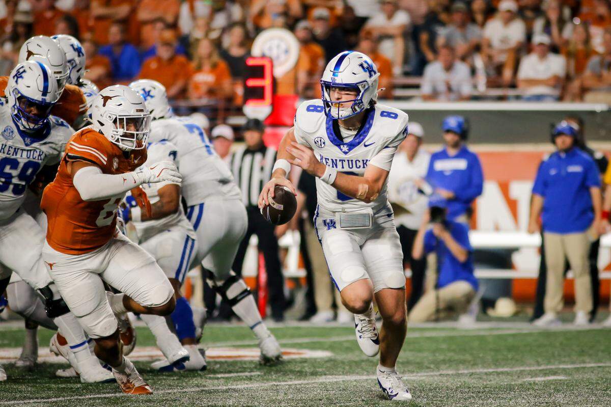 Kentucky quarterback Cutter Boley (8) runs away from Texas defenders during Saturday’s game in Austin.