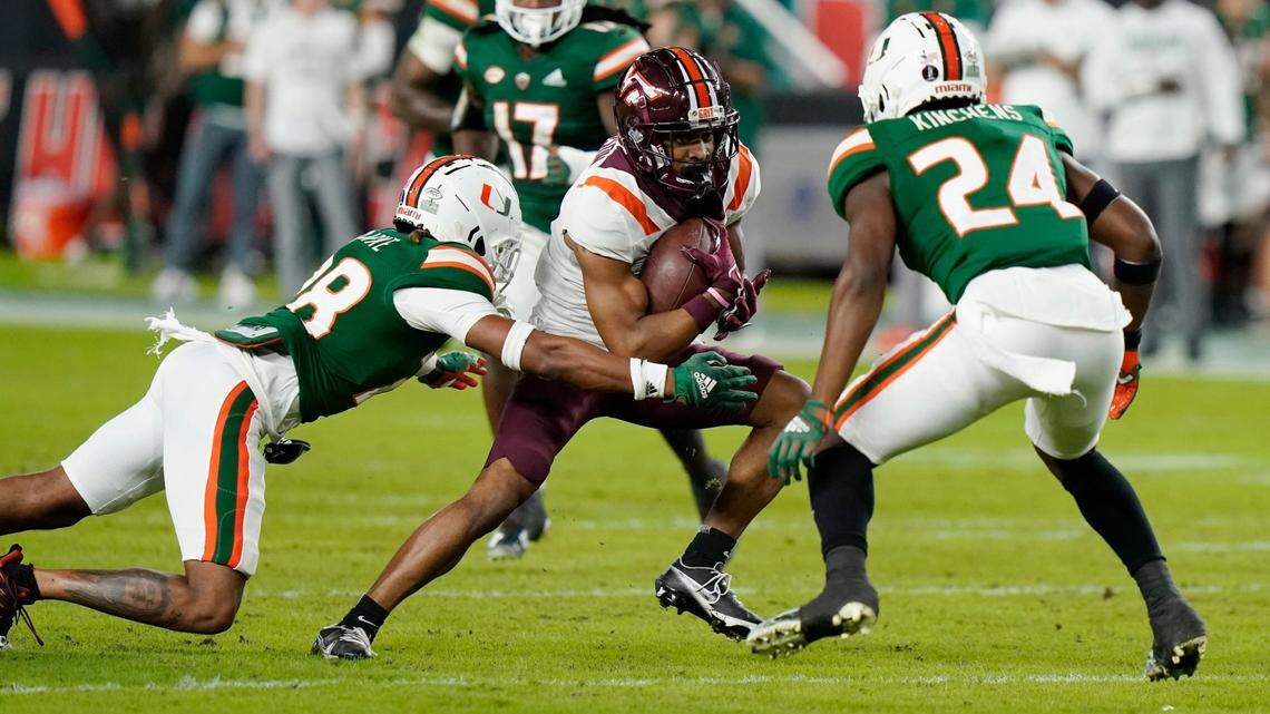 Virginia Tech wide receiver Tayvion Robinson, center, runs for a first down as he is tackled by Miami cornerback Marcus Clarke, left, tackles during the first half of an NCAA college football game, Saturday, Nov. 20, 2021, in Miami Gardens, Fla. (AP Photo/Lynne Sladky)