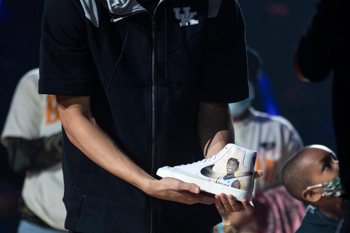The UK team presents a pair of shoes to the family of former Wildcat Terrence Clarke during Big Blue Madness on Friday. Clarke was killed in an auto accident last spring.