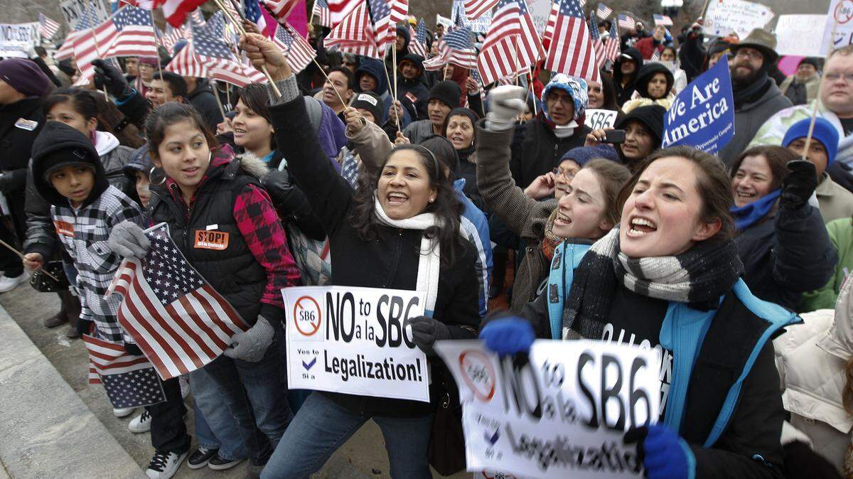 From left: Laura Carmona, holding sign at center, Paola Acha and Denisse Acha were joined by hundreds voicing their opposition Tuesday.