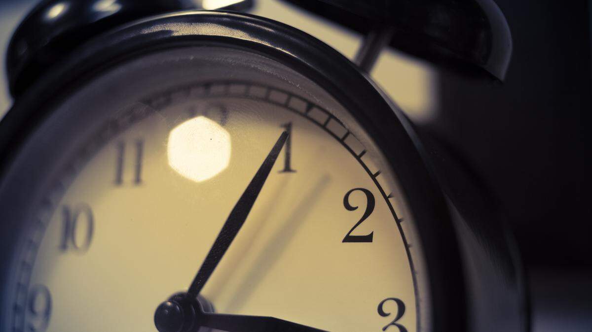 The stock image shows a close-up view of an old-fashioned alarm clock. The minute hand is on 1 and the hour on 3.