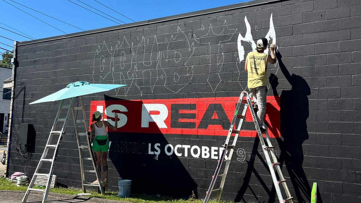 Alexandra Pangburn and Jeoff Murphy work on the current replacement mural on the side of Record Nations; it will serve as an advertisement for PRHBTN’s annual mural festival until it is replaced by a local artist’s work in October during the festival.