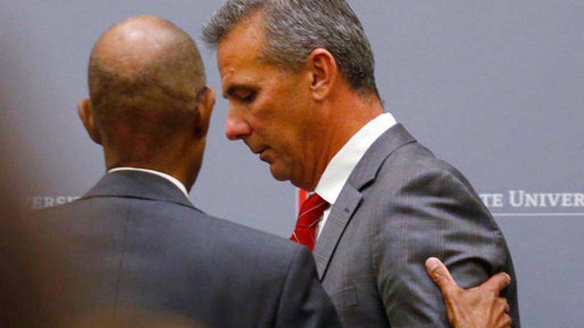 Ohio State University President Michael Drake offers words to football coach Urban Meyer, who leaves the stage following a news conference in Columbus, Ohio, Wednesday, Aug. 22, 2018. Ohio State suspended Meyer on Wednesday for three games for mishandling domestic violence accusations, punishing one of the sport’s most prominent leaders for keeping an assistant on staff for several years after the coach’s wife accused him of abuse. Athletic director Gene Smith was suspended from Aug. 31 through Sept. 16.