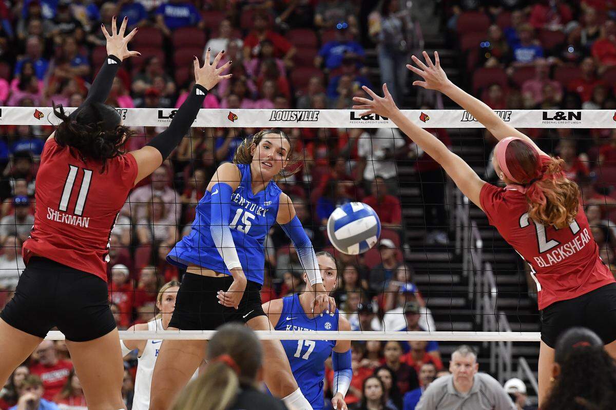 Kentucky middle blocker Lizzie Carr (15) spikes the ball between the defense of Louisville middle blocker Hannah Sherman (11) and middle blocker Kalyssa Blackshear (24) in the Wildcats’ win over the Cardinals on Thursday. 