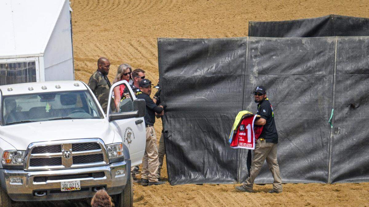 A track worker carries the saddle blanket of Havnameltdown away as the horse is euthanized after suffering a catastrophic leg injury during the sixth race prior to the 148th running of the Preakness Stakes horse race at Pimlico Race Course, Saturday, May 20, 2023, in Baltimore. (Jerry Jackson/The Baltimore Sun via AP)