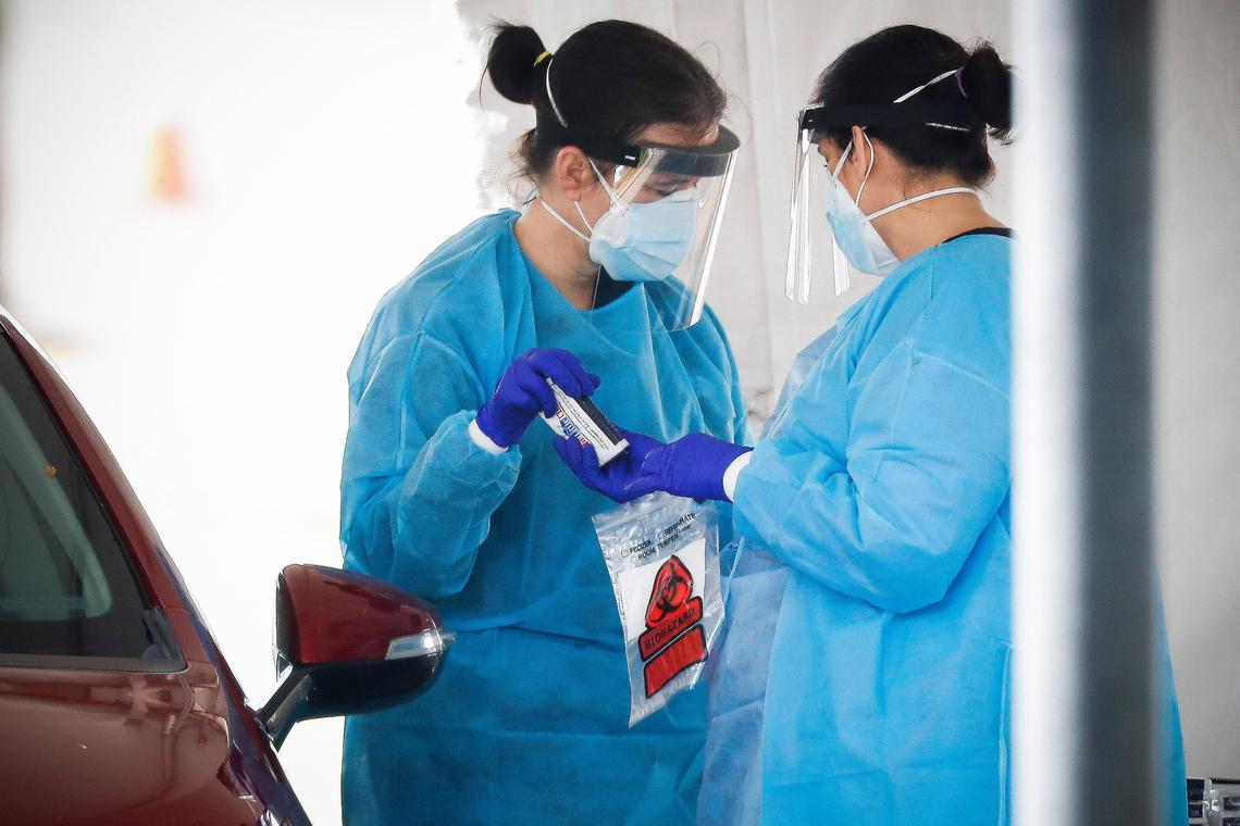 Health care workers handle a COVID-19 test at a drive-in testing site in the parking lot of the Center for Rural Development in Somerset, Ky., Tuesday, April 21, 2020.