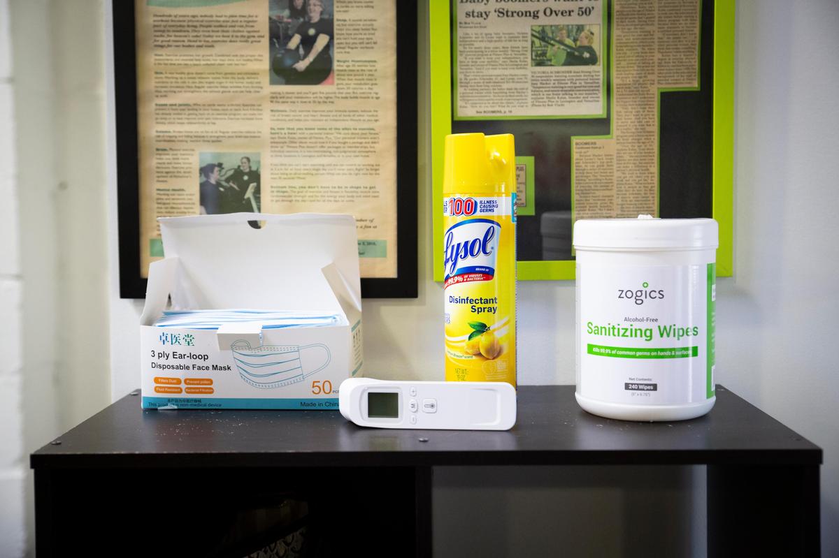 A thermometer, box of masks and sanitizing spray and wipes sat near the entrance of Fitness Plus in Lexington on Monday.