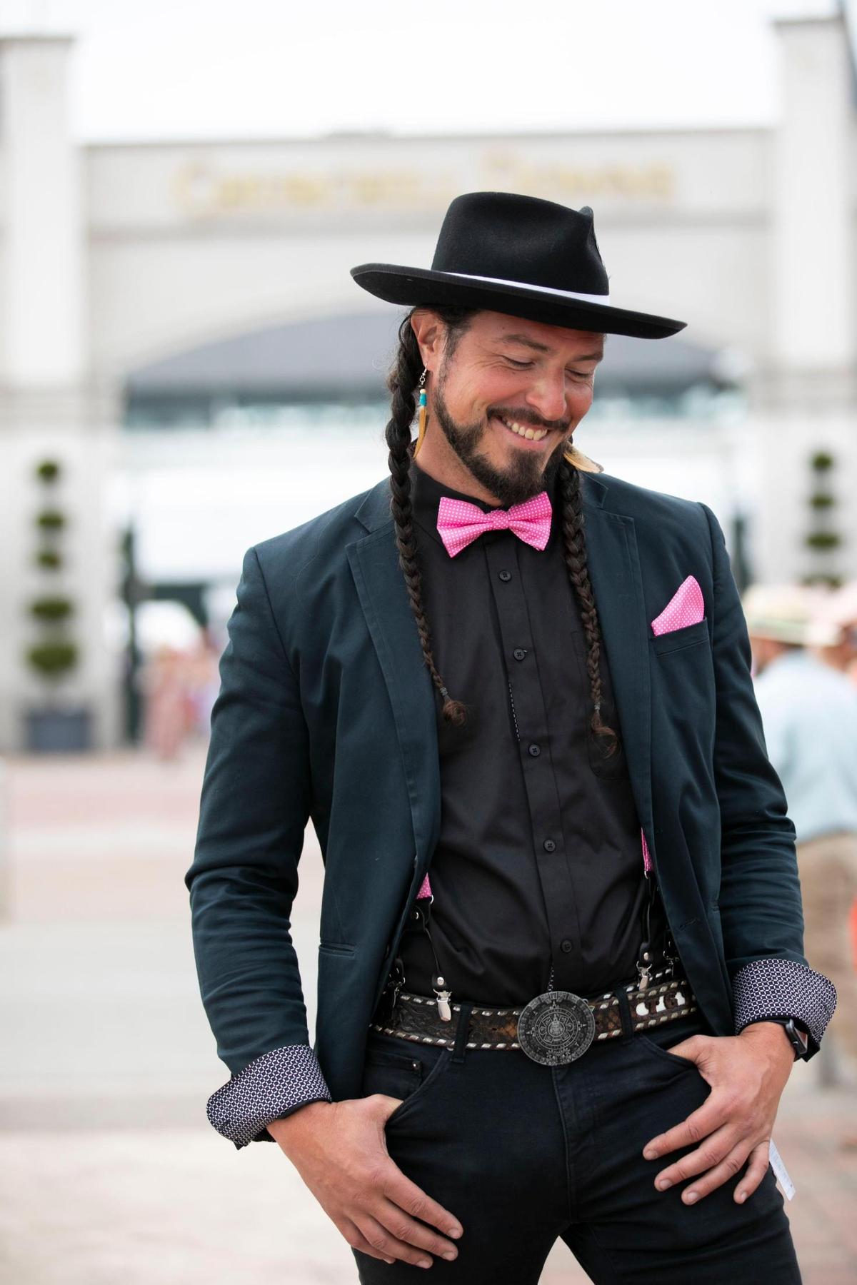 An attendee of the 149th running of the Kentucky Derby at Churchill Downs in Louisville, Ky., Saturday, May 6, 2023, uses pink accessories to highlight his all-black look.