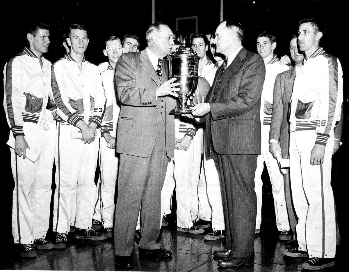 Kenneth L. (Tug) Wilson, left foreground, who was the secretary-treasurer of the NCAA at the time, presented the championship trophy to Coach Adolph Rupp after Kentucky defeated Baylor, 58-42, in Madison Square Garden on March 23, 1948.