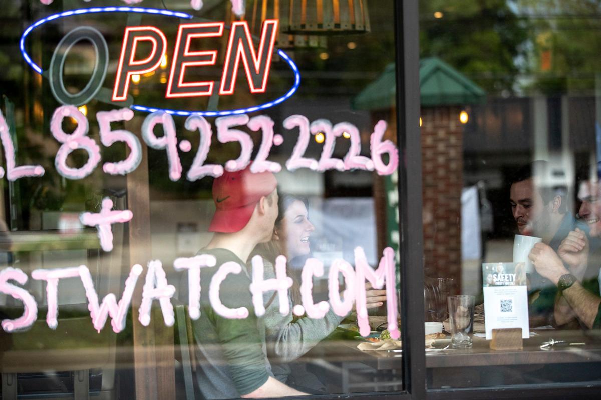 Andrew Bevins, from left, Cierra Landrum, Adam Caskey, and Wes Wattenberger chat Friday while waiting for their meals to arrive at First Watch on South Broadway. Restaurants reopened to dine-in customers Friday.