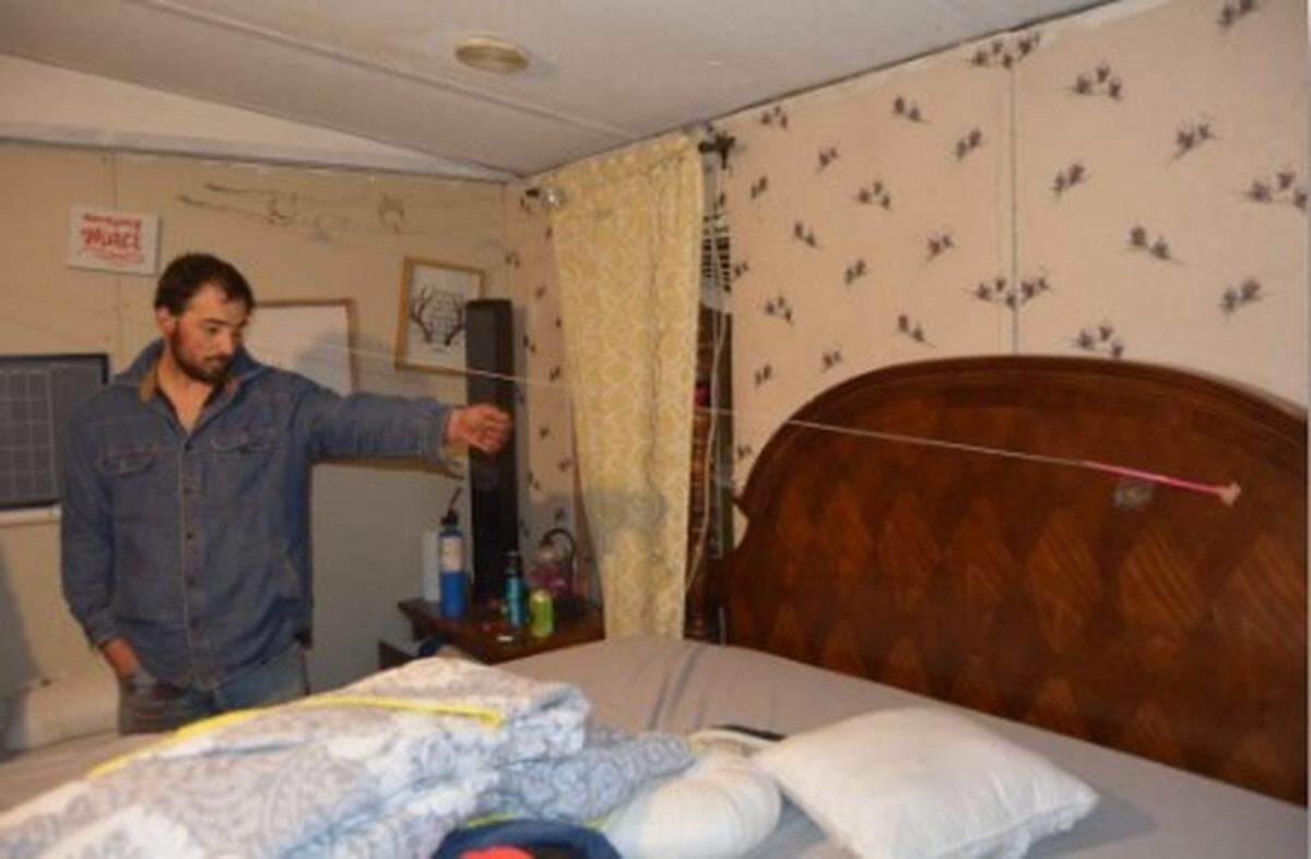 Daniel Nantz, 32, points at a bullet hole in the bedroom of his trailer, allegedly where he first shot his pregnant girlfriend, Geri.