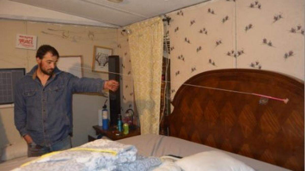 Daniel Nantz, 32, points at a bullet hole in the bedroom of his trailer where he first shot his pregnant girlfriend, Geri Johnson.