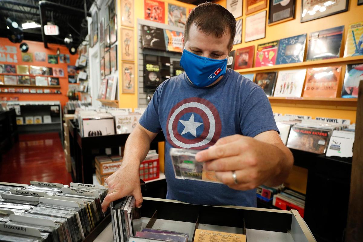 John Hood looks through stacks of albums June 11 at CD Central. When the coronavirus outbreak hit, the independent record store near the campus of the University of Kentucky went to curbside service. They have reopened with social distancing.